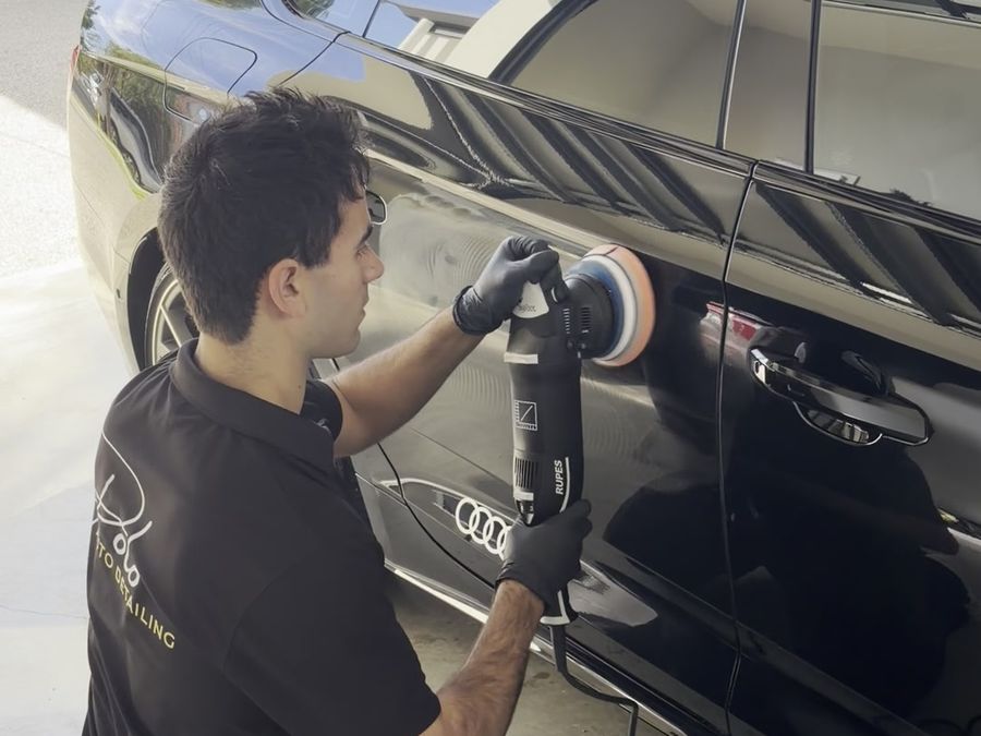 Machine polishing the door of a black Audi