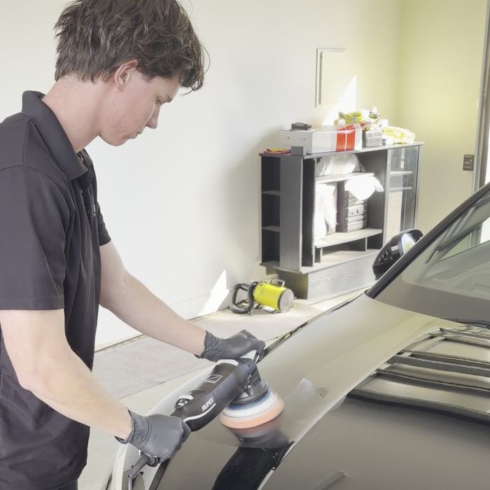 Machine polishing the bonnet of a black Audi